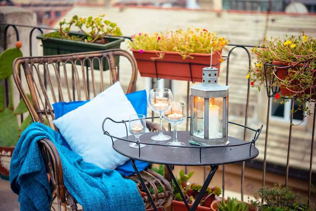Beautiful terrace or balcony with cozy rattan armchair and candles on small iron table
